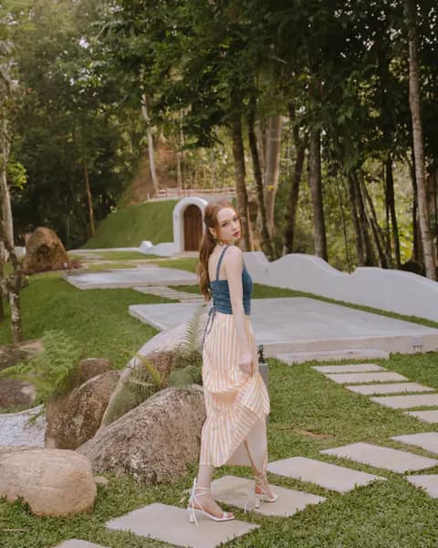 Creator wearing a teal top and striped skirt in a garden