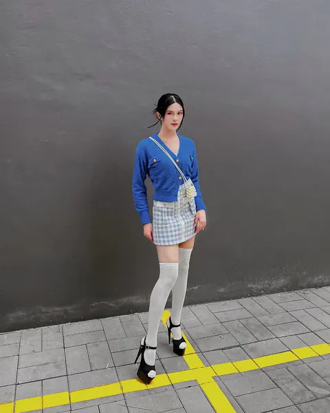 Creator wearing a blue cardigan, plaid skirt and white knee-high socks