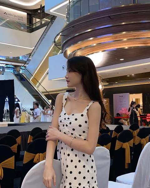 Creator posing at a fashion event in a white polka-dot dress